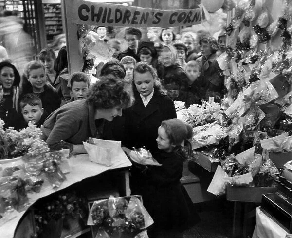 Children crowd a florists stall to buy thier flower for Mothering Sunday. 7th March 1959