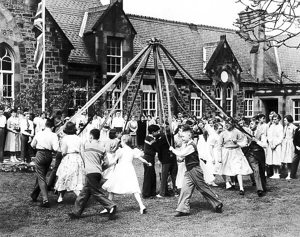 Children dance round the May pole in front of the school
