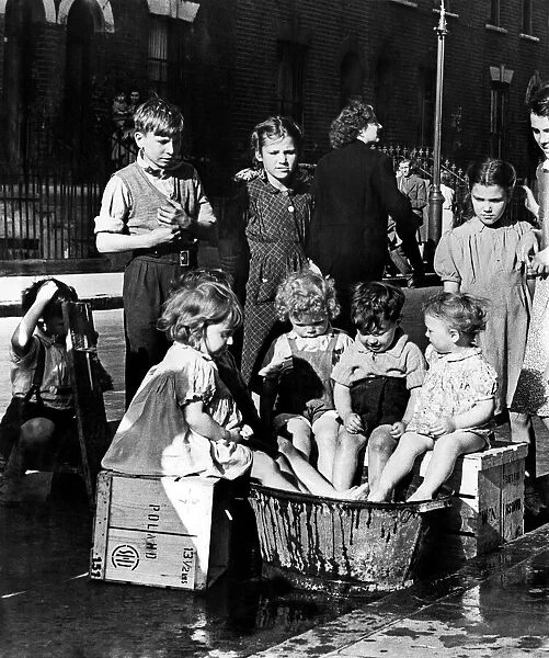 Children in East London take turns to keep cool with a large bucket of water 22nd June