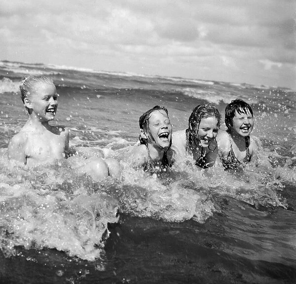 Four children enjoy a swim in the sea at Blackpool beach in the summer holidays