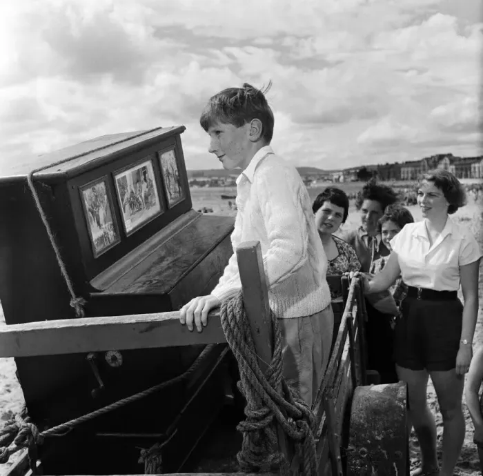 Framed Print : Children on Exmouth beach looking at an ancient Barrel Organ which Mr Percy Tucker