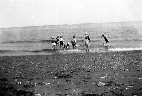 Children having fun in the sea at an unknown beach in England. Circa 1929