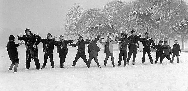 Children on holiday from school throwing snowballs and playing in the snow on Tooting Bec