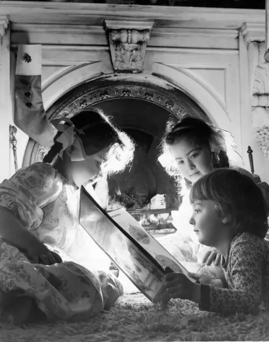 Framed Print : Three children listen to a fairytale in front of roaring fire at Christmas time