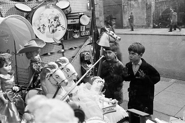 Children look longingly at toys into shop window at Christmas, 16th December 1960