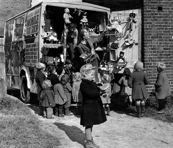 Children looking a the toys on the back of a mobile toy shop