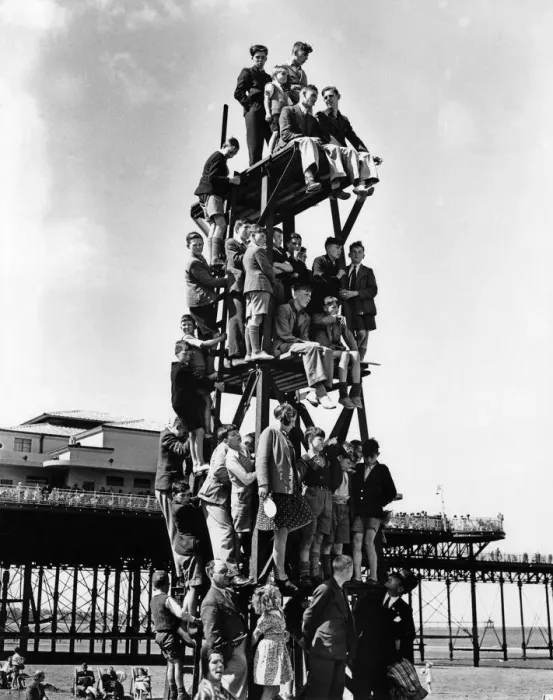 Framed Print : Children make a human pyramid on a lifeguard look-out tower at a Butlins holiday camp Framed Print : Children make a human pyramid on a lifeguard look-out tower at a Butlins holiday camp