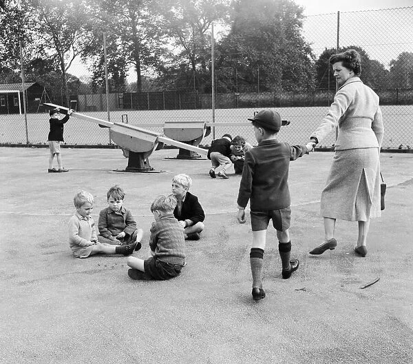 Children in the playground playing a game of marbles as one boy is dragged away by his