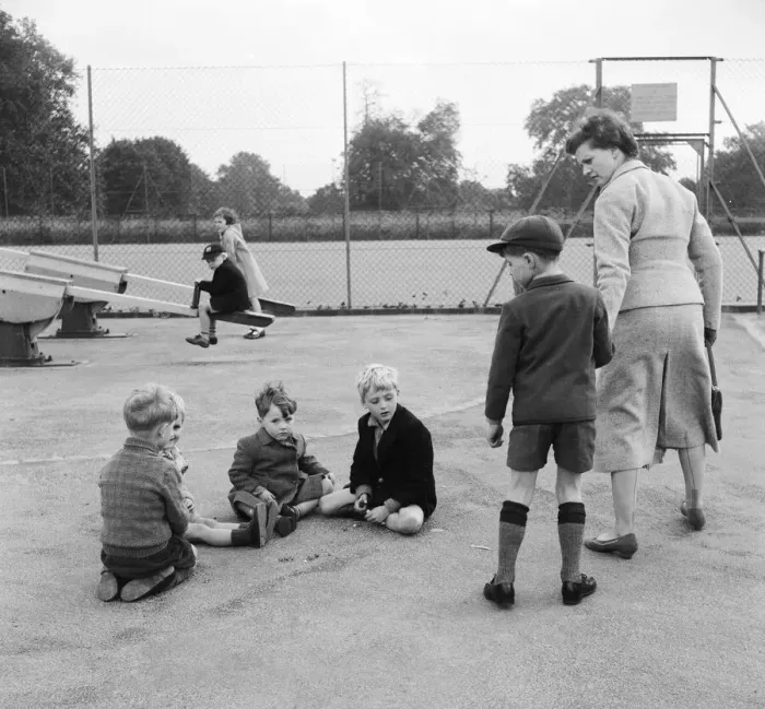 Framed Print : Children in the playground playing a game of marbles as one boy is dragged away by his Framed Print : Children in the playground playing a game of marbles as one boy is dragged away by his