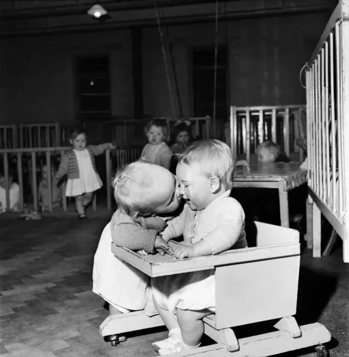 Framed Print : Children playing at a day nursery in Leeds. One sitting in the chair as another toddler Framed Print : Children playing at a day nursery in Leeds. One sitting in the chair as another toddler