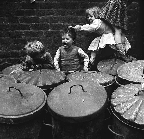 Children playing dustbins on a slum housing estate 1st June 1962