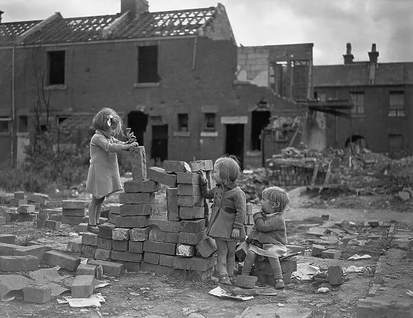 Children playing games on a bomb site in London, three little girls play with bricks