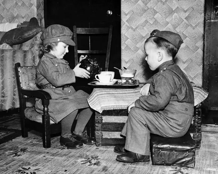 Framed Print : Children playing games at home dressed in army uniform and pouring tea during WW2 Framed Print : Children playing games at home dressed in army uniform and pouring tea during WW2