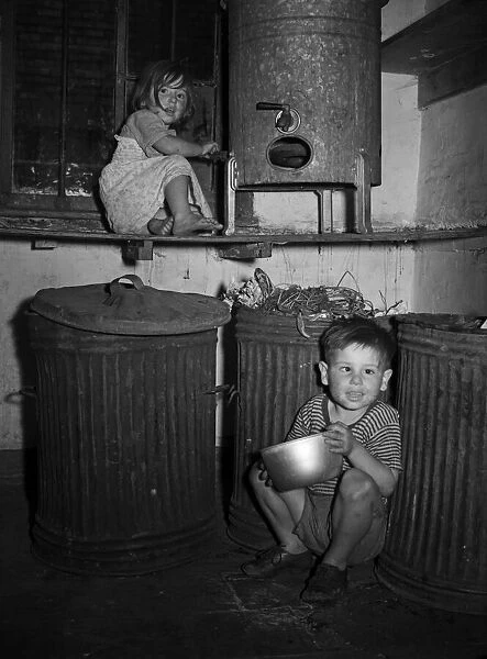 Children playing indoors by dustbins in a house in Hull. 9th July 1953