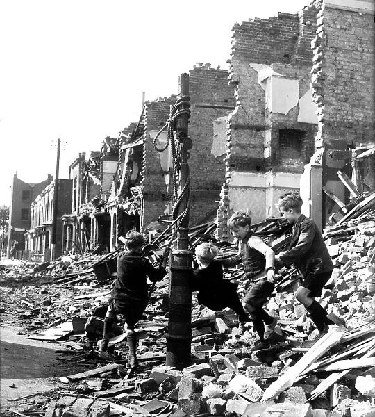 Children playing on a makeshift swing amidst rubble during the blitz attack of the German
