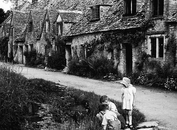 Children playing on the road outside a picturesque row of cottages in Arlington Row in