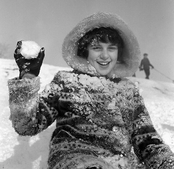 Children playing in the snow on Hampstead Heath, A girl holds a snowball during a