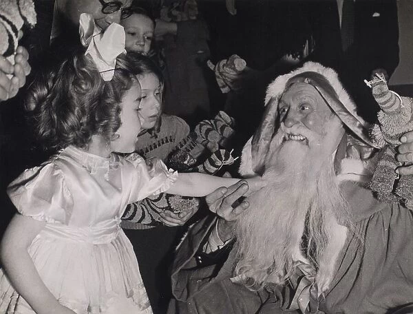 Children pulling Father Christmass beard at a party given by the Merchant Navy Club