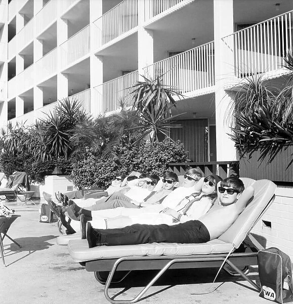 Children relaxing in sun loungers by the side of their hotel swimming pool on holiday