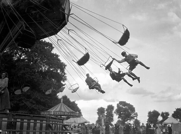 Children ride the Chair-a-Plane ride at the Surbiton fair. Circa 1930