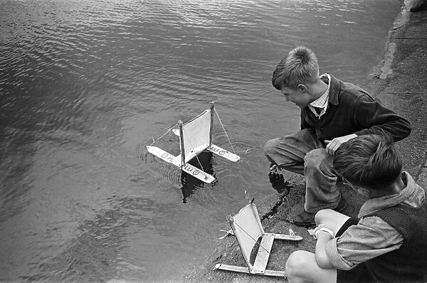 Children sailing their toy yachts on the Round Pond in Kensington Gardens, London