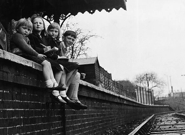 Children sitting on a wall looking at trains arriving and departing from Barnwell