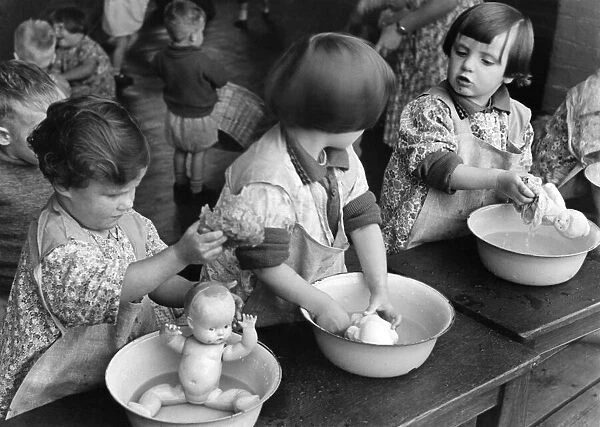 Children washing their dolls in a small tin bath during a nursery class in Northfields