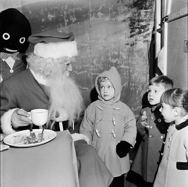 Children watching Father Christmas eating his dinner. 29th December 1955