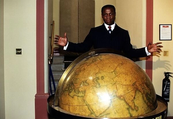 Chris Eubank standing behind a globe