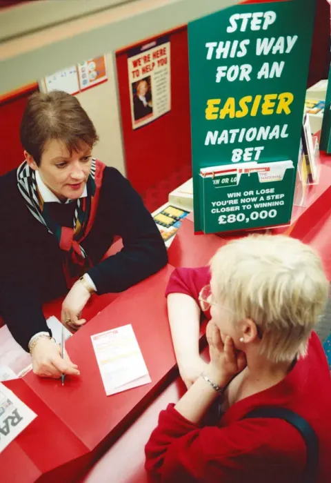 Framed Print : Chris Hudson, mangers of Ladbrokes in the Bigg Market, gives out last minute tips to Framed Print : Chris Hudson, mangers of Ladbrokes in the Bigg Market, gives out last minute tips to
