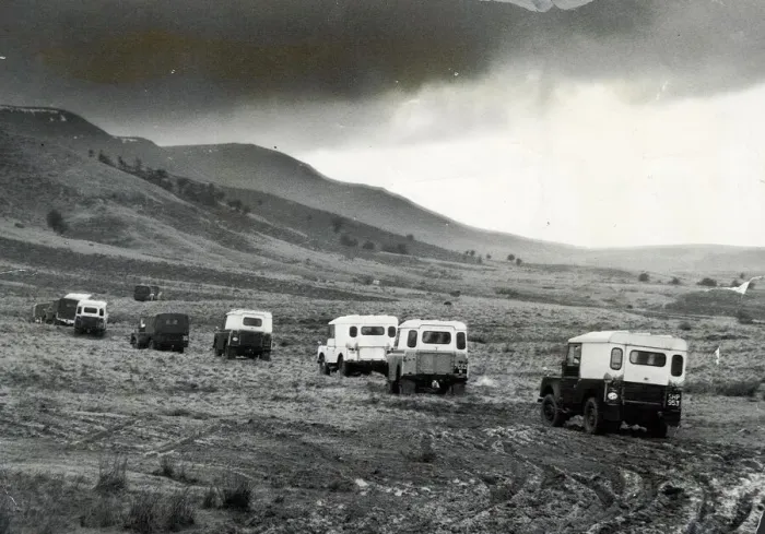 Framed Print : Churning through layers of mud, a line of Land Rovers move cross country towards Framed Print : Churning through layers of mud, a line of Land Rovers move cross country towards