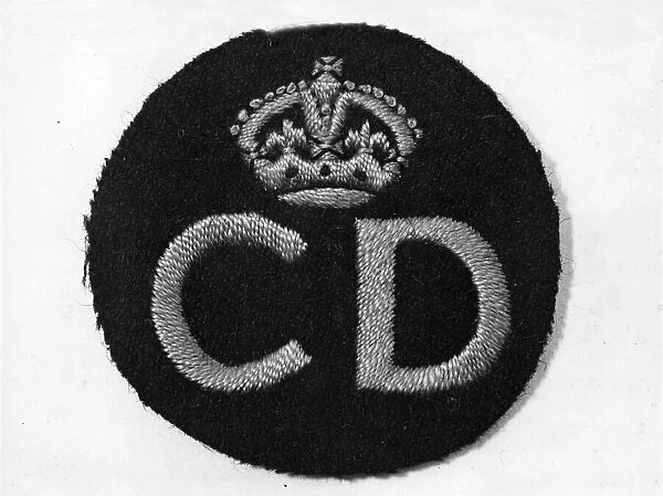 Civil Defence service badge, woven in a gold colour, worn on the left breast of a uniform