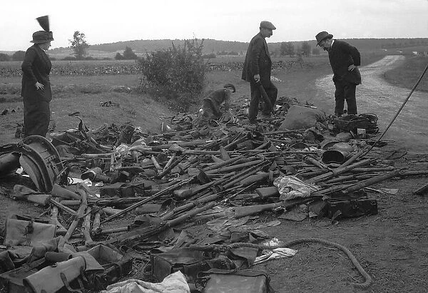 Civilians look at heap of rifles left in the field by the Germans during World War