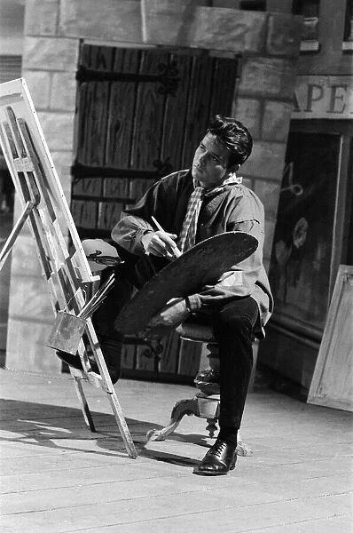 Cliff Richard on the set of the film Summer Holiday, painting with a brush and easel