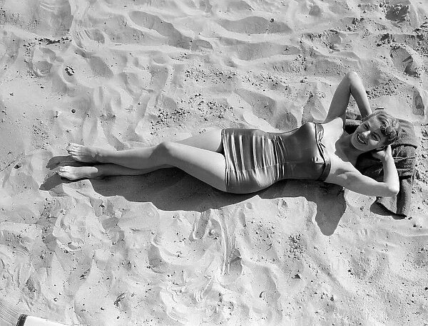 Clothing Beach wear swimsuits fashion April 1952 Model laying on the beach