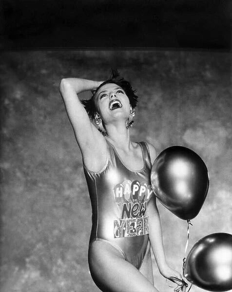 Clothing Beach. Woman models a shiny swimming costume with 'Happy New Year'