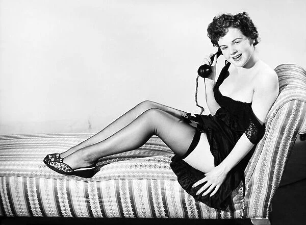 Clothing: Fashion: Stockings and garters. Model sitting in armchair with telephone