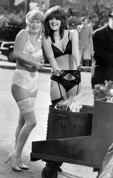Clothing Underwear: Chilly models in lingerie warm up from a fire in a bin in the street