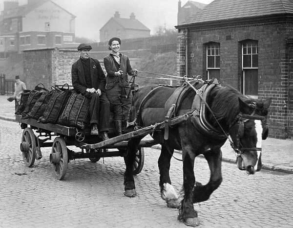 Coal Women. Woman on a cart laiden with sacks of coal, being pulled along by a horse