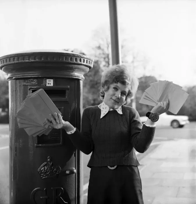 Framed Print : Communications: Woman holding a large collection of letters as she stand by a Royal Mail