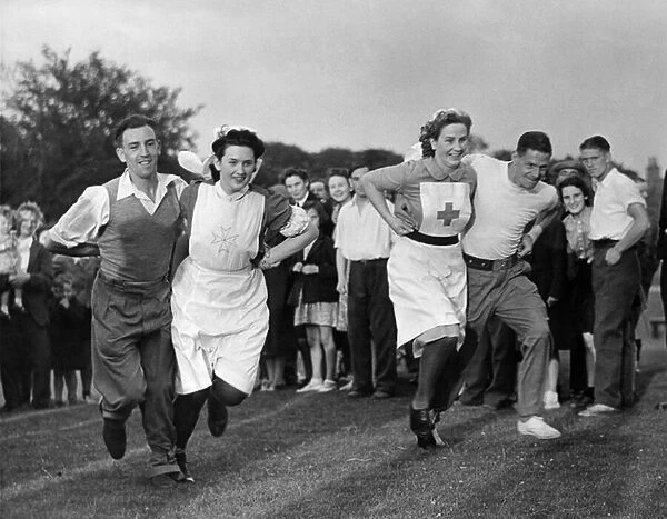 Convalescent soldiers run a three legged race with their nurses at a village sports day