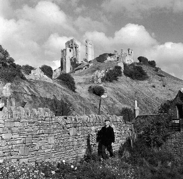 Corfe Castle Dorset rises behind a drystone wall. Corfe Castle