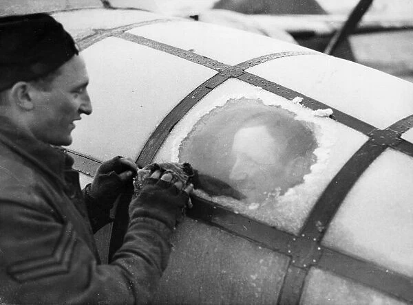 Corporal H Wells of Plumpton, Sussex, wiping ice from the perspex of a Mitchell bomber in