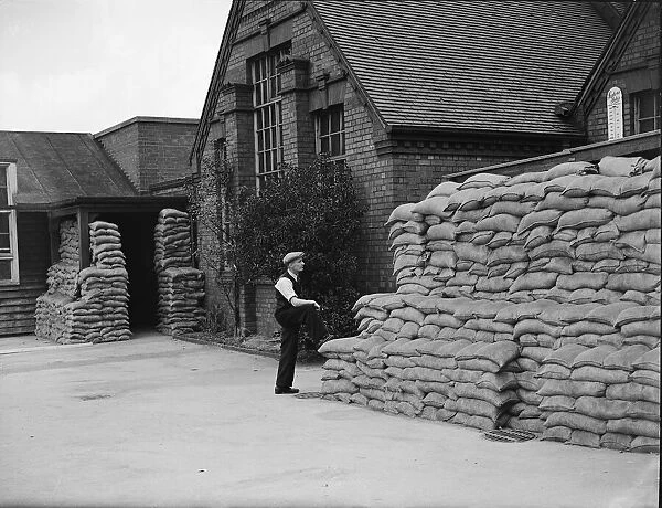 A council workman surveys the sandbag protection at an un-named school in the West