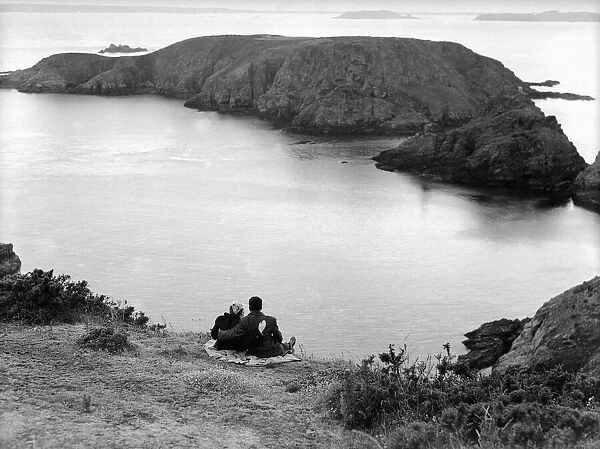 A couple enjoy some time together looking out across the sea on the Channel Island of