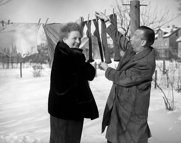 A couple hanging out their washing - socks, smiling in the snow 8th January 1955