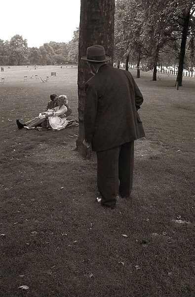 A Couple Kissing in the park all the while being watched by a dirty old man