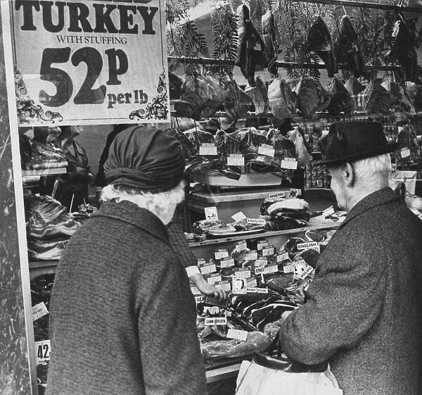 Couple looking at meat products on display in butchers shop, Cardiff, Wales