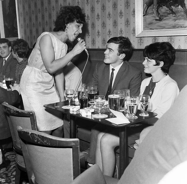 A couple get the treatment from a singer in Dundee Lounge Bar. 6th June 1967