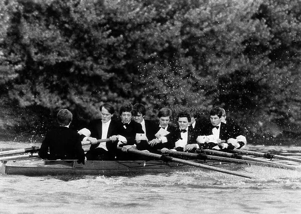 The crew from Oxford row down the thames in their boat dressed in dinner suits